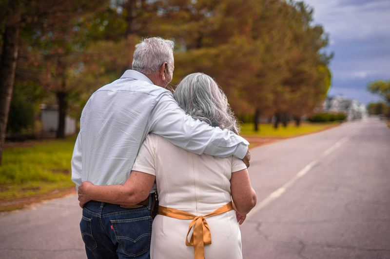 A caregiver and an older woman walking slowly together outdoors
