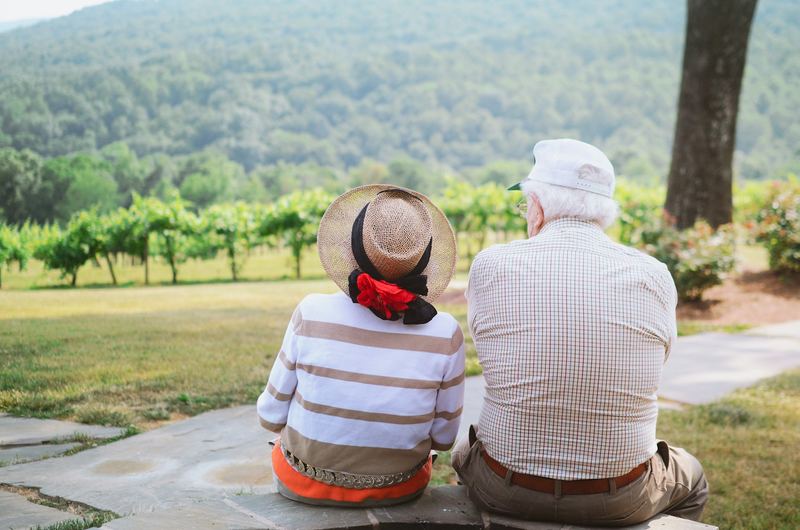 An older couple walking a path between vines